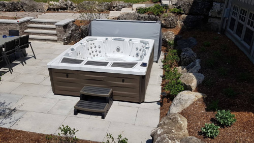 Hot tub installed in a backyard on a patio.