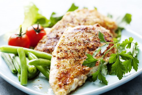 Healthy grilled chicken served on a place with vegetables.