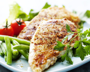 Healthy grilled chicken served on a place with vegetables.